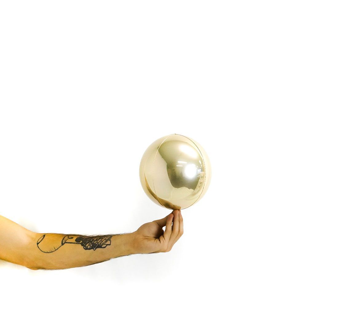 Gold sphere held by a hand on a white background